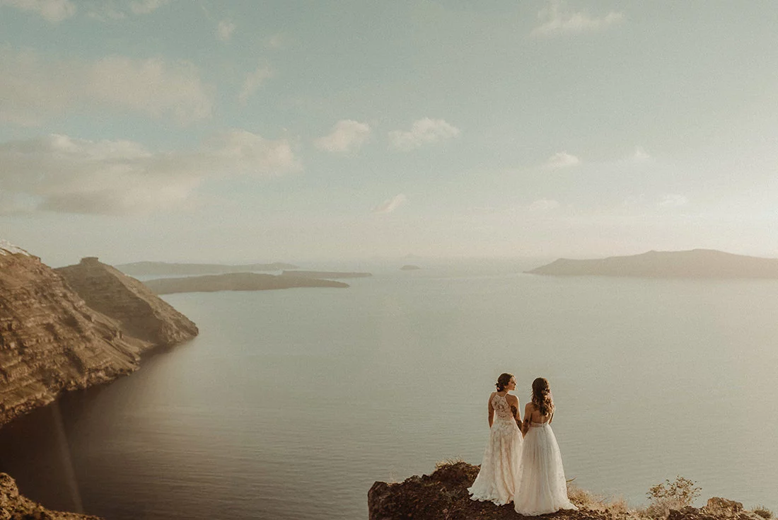Stunning couple of two brides in Imerovigli illustrating the guide of best places to get married in Santorini
