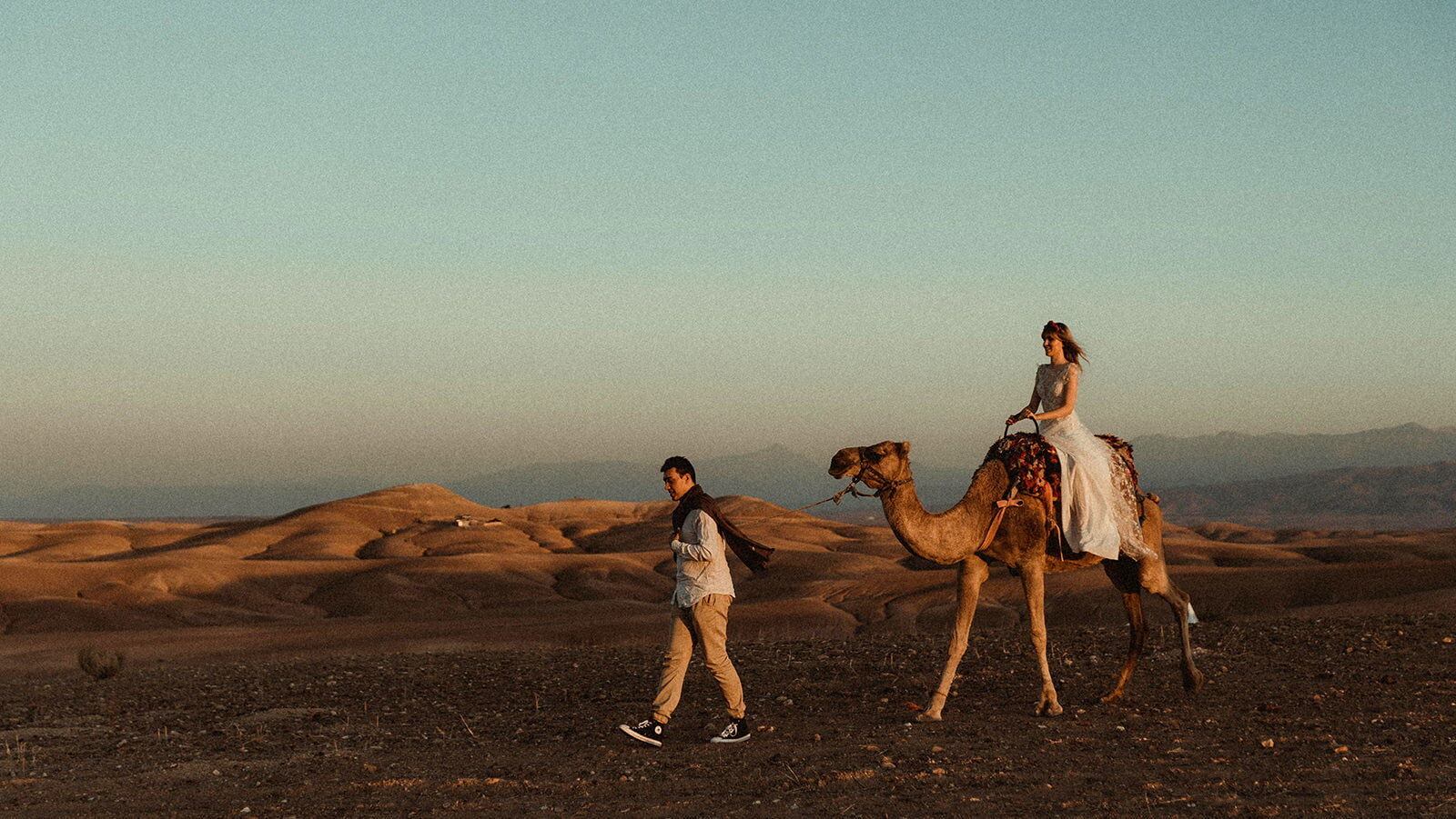 Morocco Elopement Wedding Couple walking in the Moroccan Desert with a dromedary