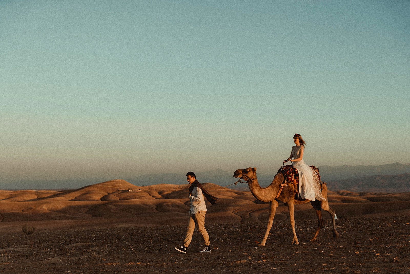 Morocco Elopement Wedding Couple walking in the Moroccan Desert with a dromedary