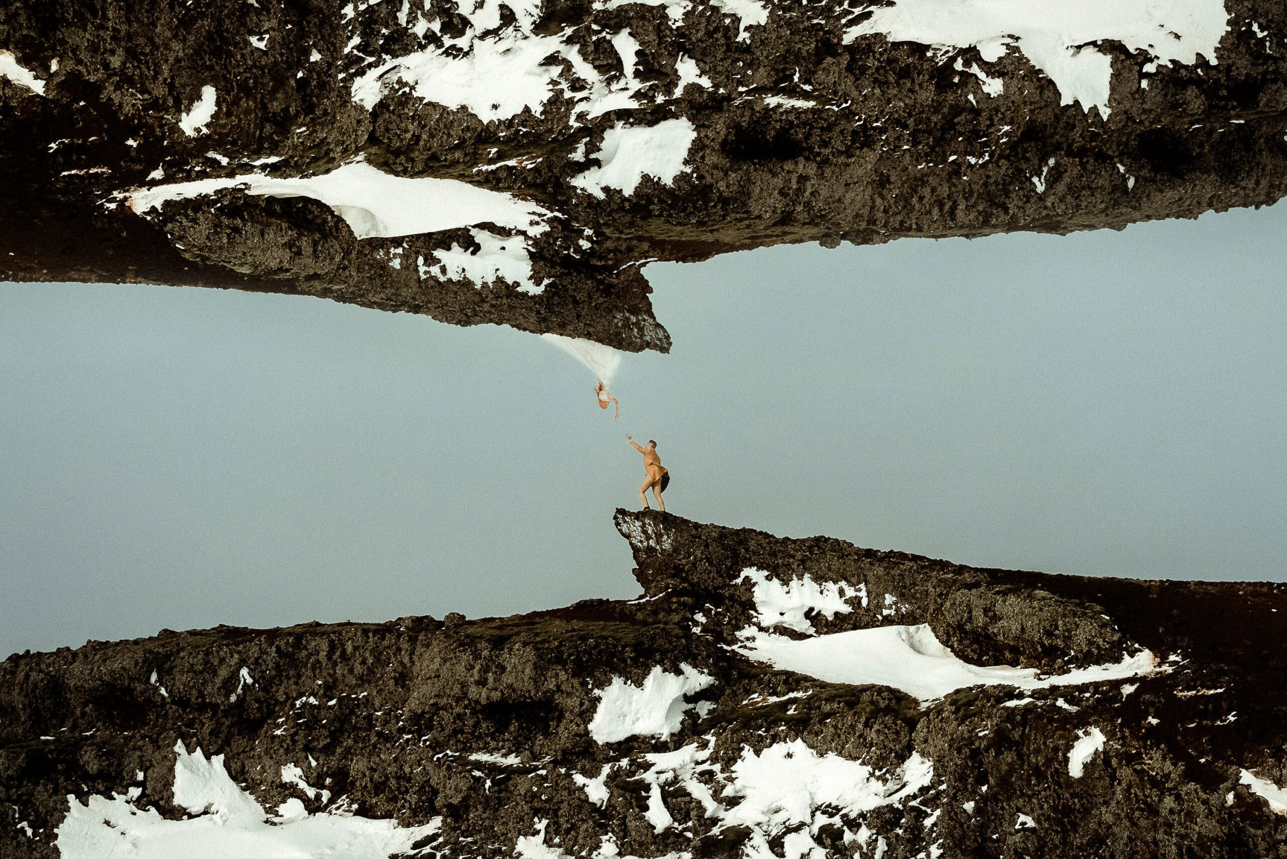 A couple reaching for each other on top of a hill after their Pagan Winter Iceland Wedding
