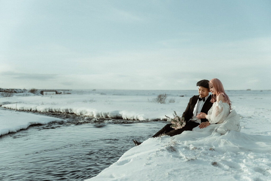 pagan winter wedding in Iceland - couple sitting on the banks of a river