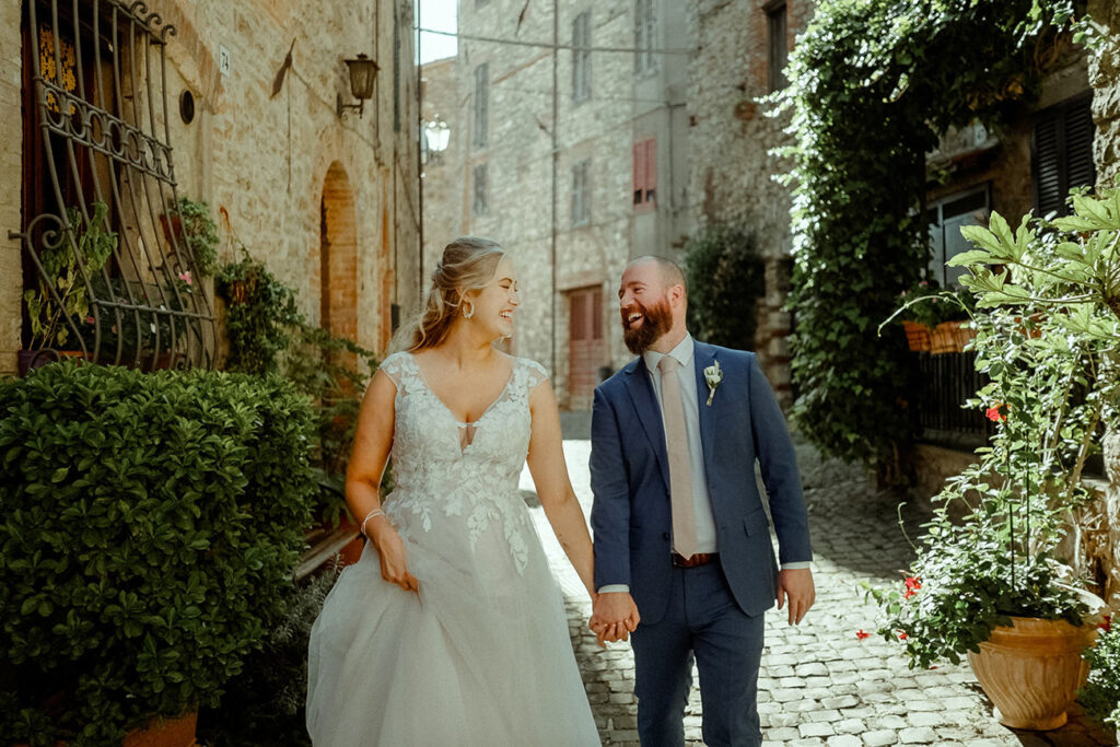 Newly wed couple holding hands in the medieval streets of a small village of Umbria Italy