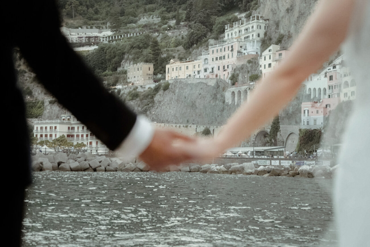 wedding couple holding hands in front of Amalfi