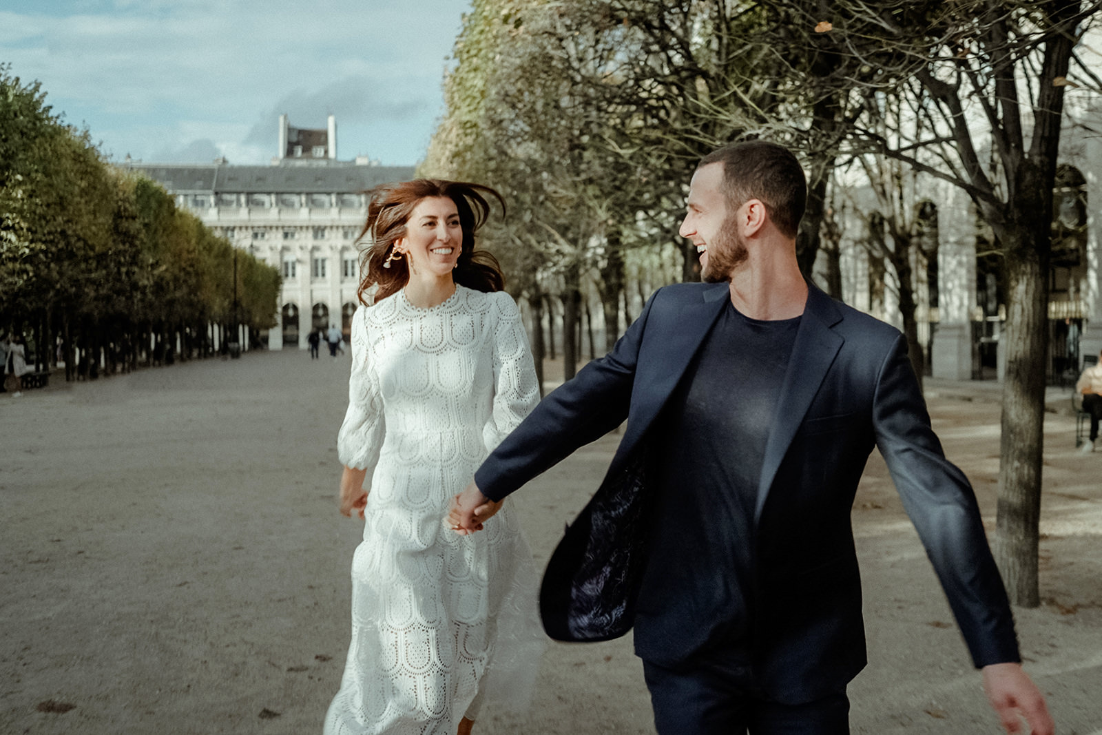 Couple running in the gardens of the Palais Royal for their outdoor wedding in Paris