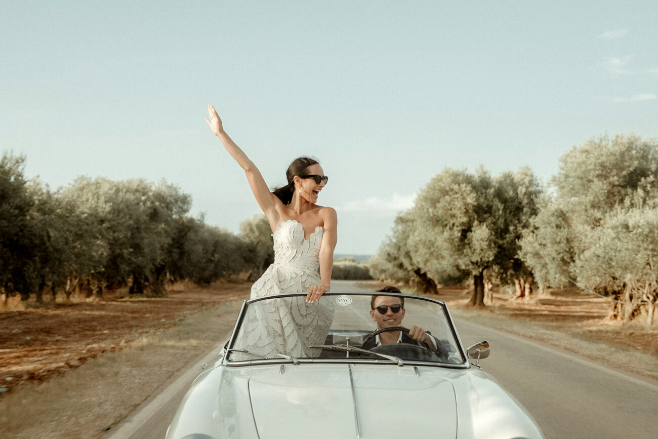 Tuscany Wedding Videographer 16 Best Tuscany Wedding Videographer filming a couple driving in an Italian vintage car between olive trees