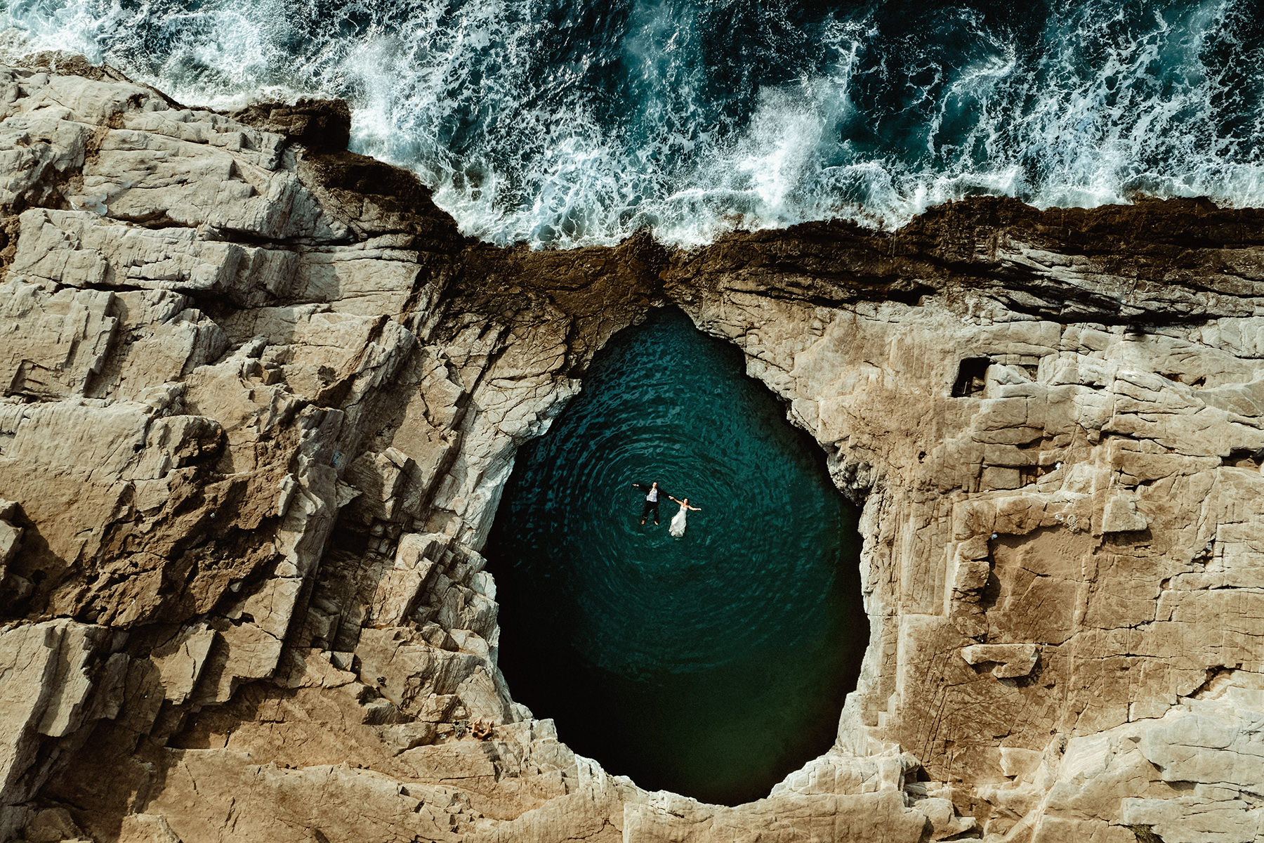 A couple in Wedding Attire floating on a naturally formed pool, Giola Lagoon in Thassos, Greece, filmed by an elopement Videographer