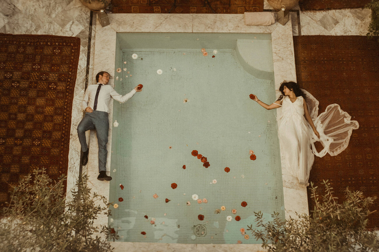 A couple lying on the floor on the two sides of a pool in Morocco filmed by an Elopement Videographer for Intentional and Intimate Celebrations