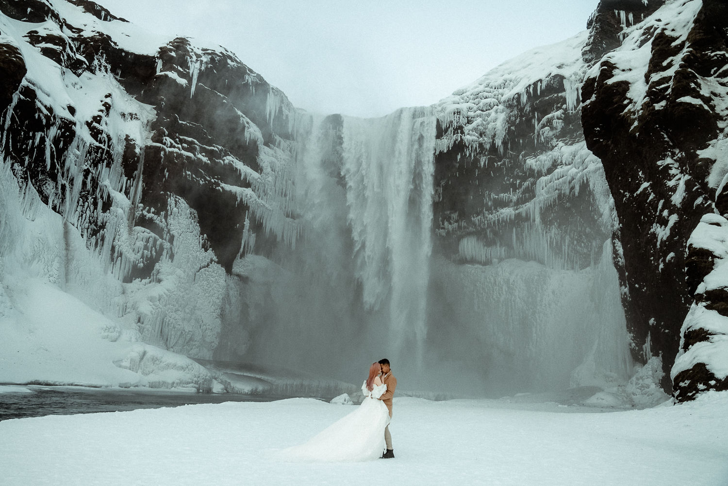Wedding Couple in front of a frozen waterfall in Iceland filmed by a Europe Wedding Videographer