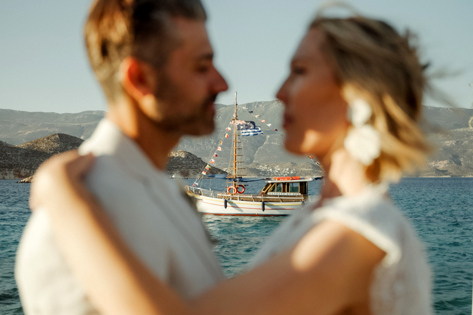 Boat with Australian and Greek flags, visible between the heads of a couple after their Kastellorizo Destination Wedding