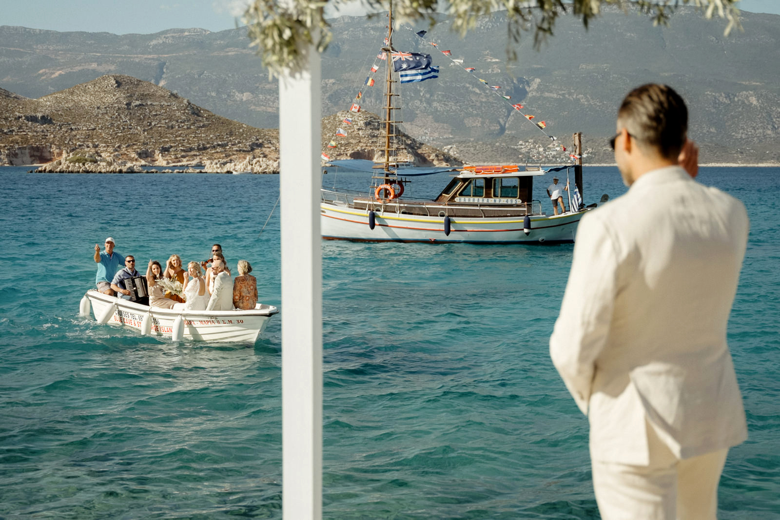 Bride party on a small boat waving at the groom before their Kastellorizo Destination Wedding