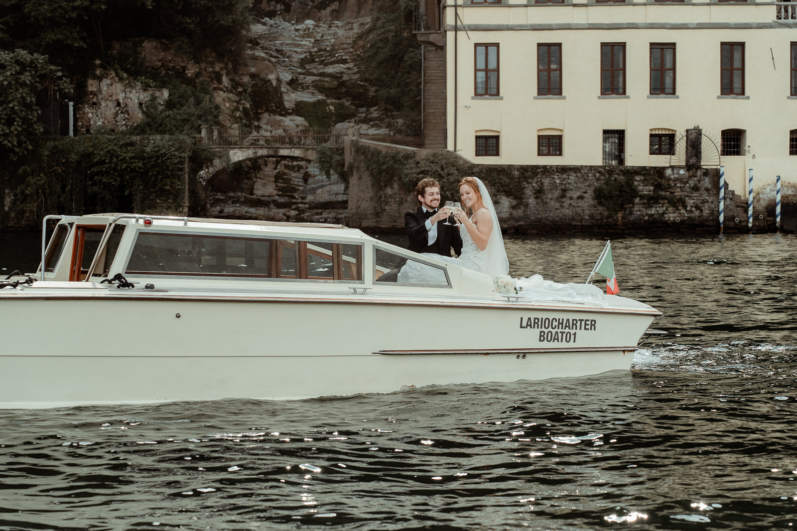 couple with champagne glasses on a boat after their Lake Como Elopement in Villa Monastero
