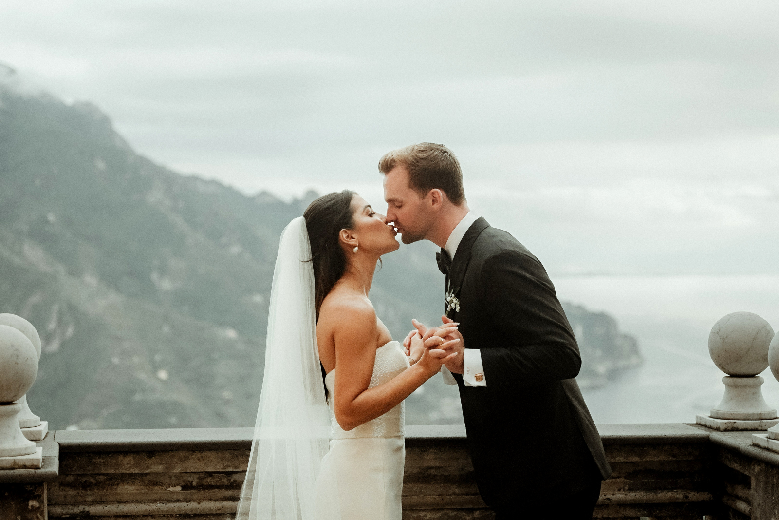 A bride and groom holding hands and kissing on the terrace after their Palazzo Avino wedding in Ravello