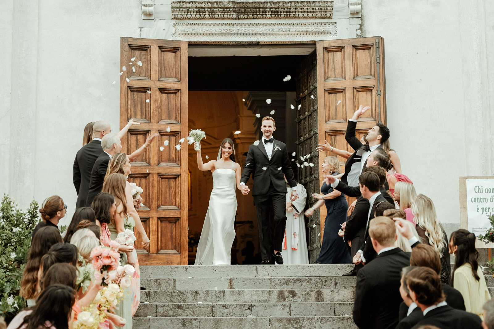 The bridal couple exit from the Duomo di Ravello while guests throw petals for their Palazzo Avino Wedding in Ravello
