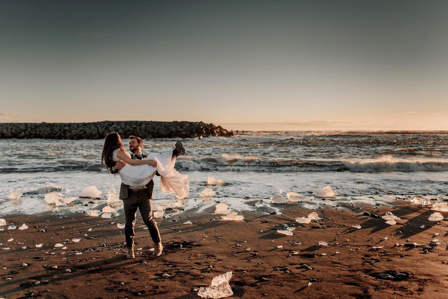 Iceland Elopement Videographer for Adventure & Intentional Celebrations 11 A groom carrying his bride in Diamond Beach, filmed by an Iceland Elopement Videographer