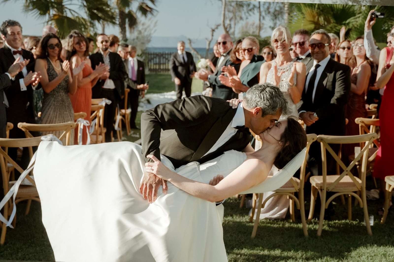 Indian Destination Wedding in Corfu at Natura Estate 4 A western ceremony ends with a kiss while guests applaud part of a multi day Indian Destination Wedding in Corfu at Natura Estate