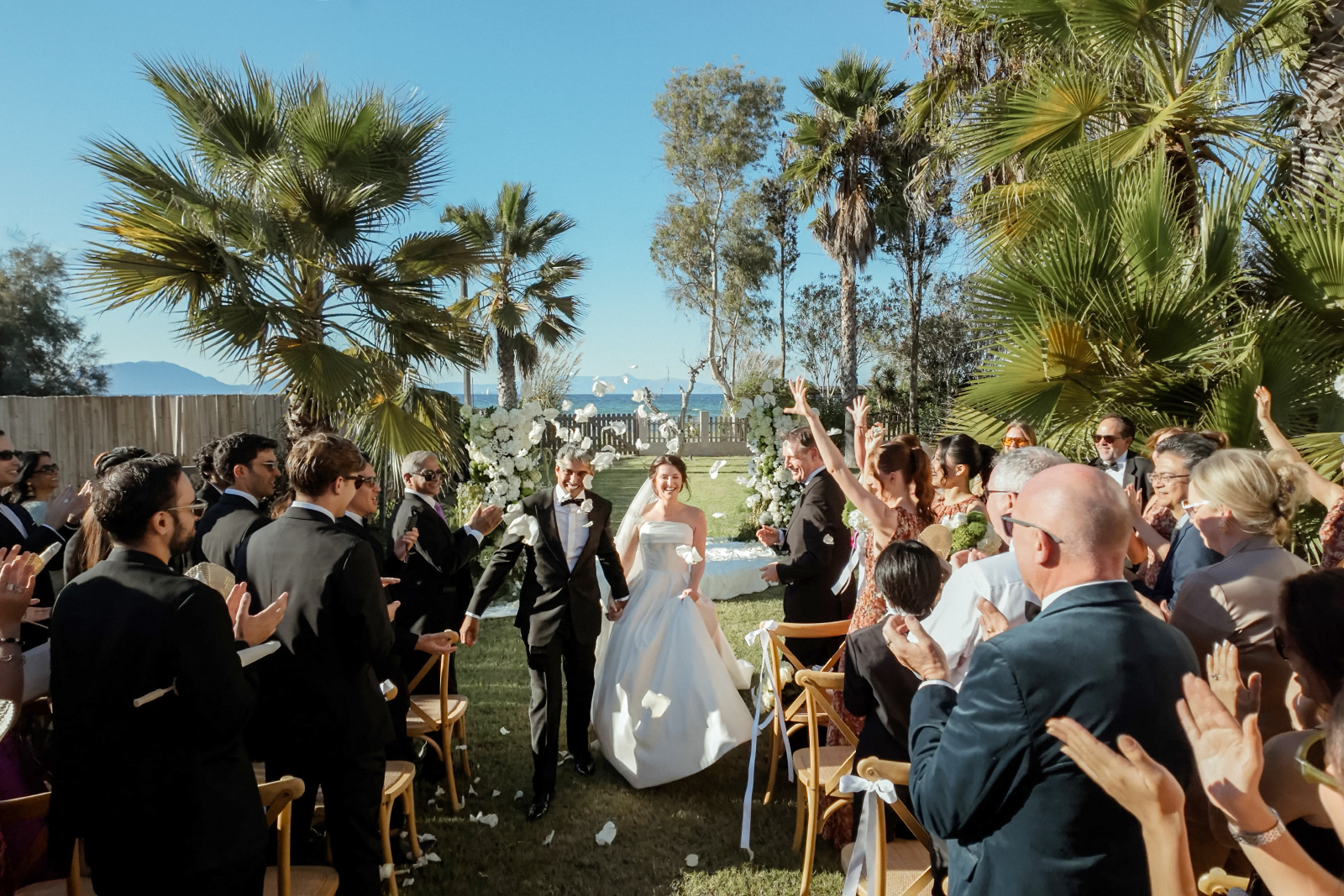 Indian Destination Wedding in Corfu at Natura Estate 3 Ceremony exit of a bridal couple and guests throwing flower petals for an Indian destination wedding in Corfu at Natura Estate