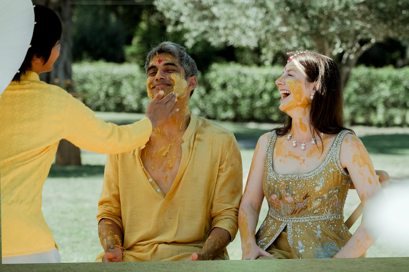 Indian Destination Wedding in Corfu at Natura Estate 5 Haldi ritual putting yellow paint on the groom's face for an Indian Destination Wedding in Corfu at Natura Estate
