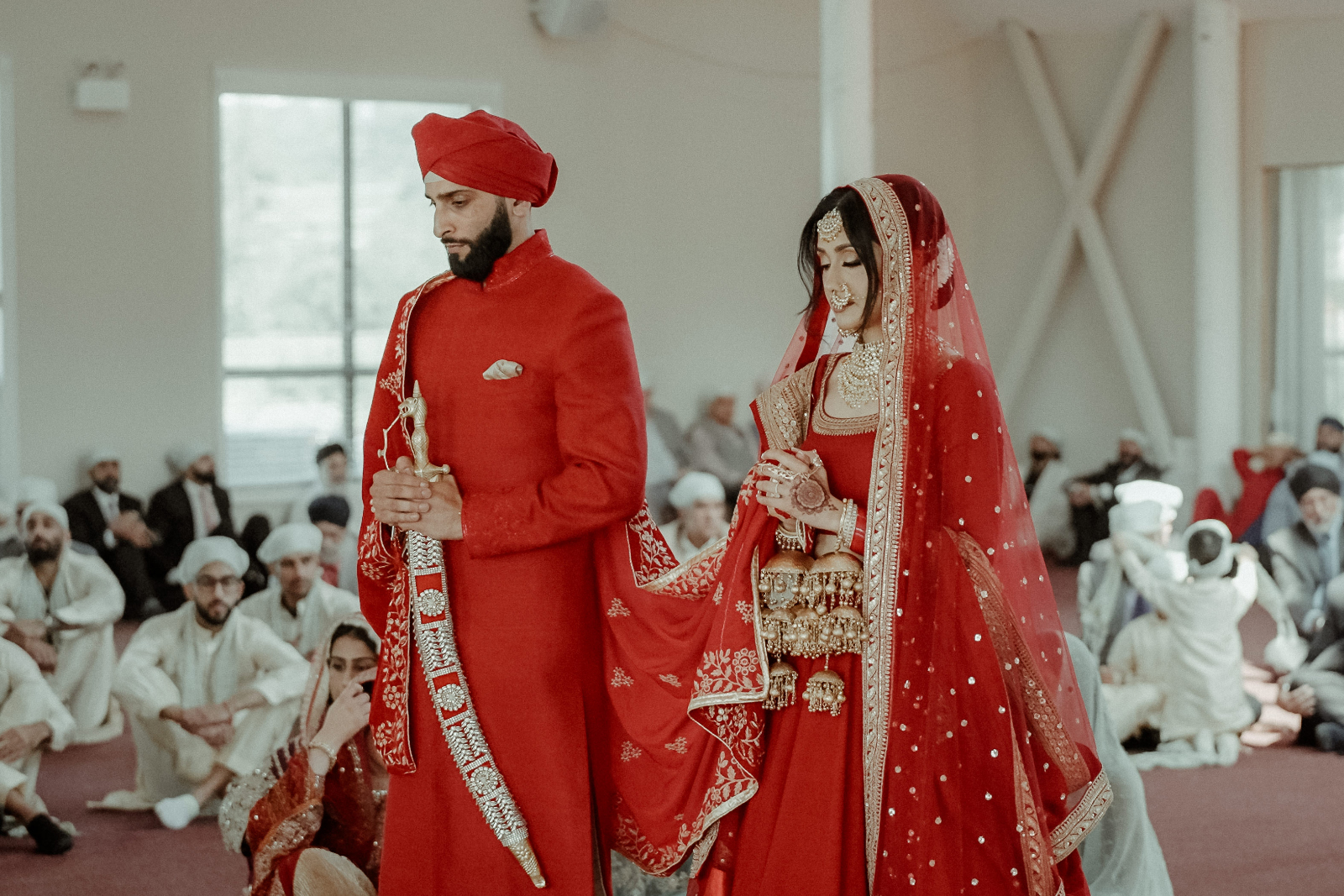Sikh Wedding in Toronto - A Story of Faith and Reflection 3 A couple in Indian wedding attire praying in the Gurdwara during their Sikh Wedding in Toronto