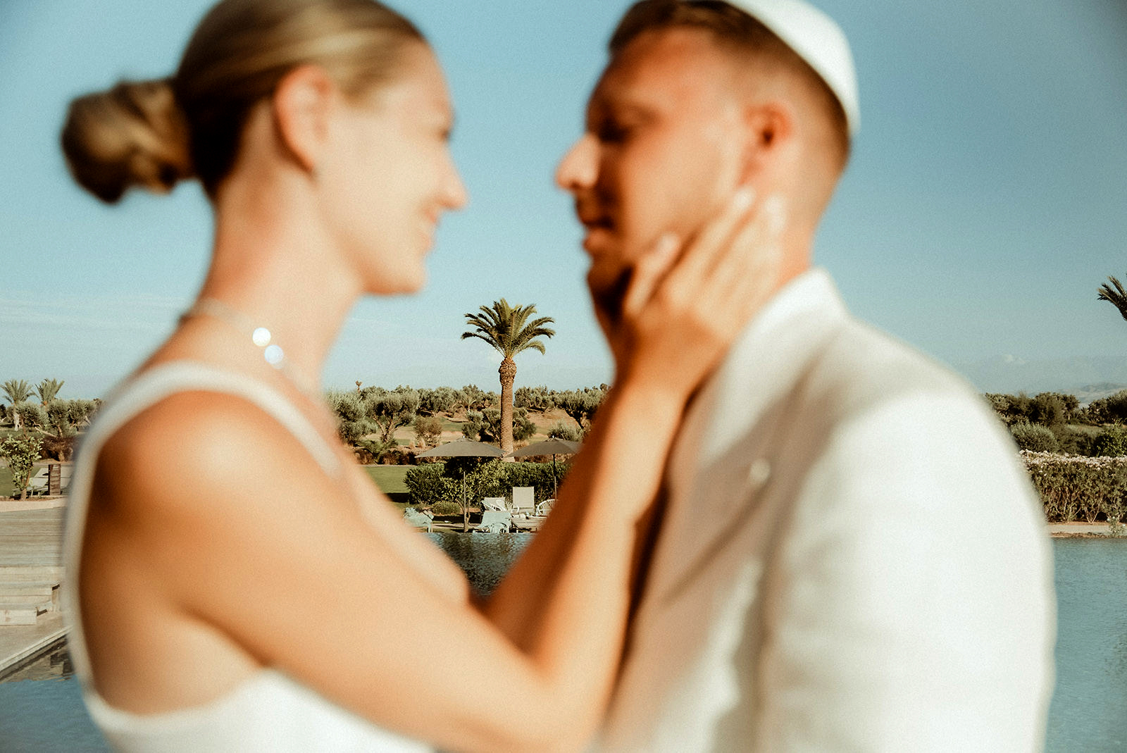 Bride and groom out of focus, with a palm tree in focus between them, after the couple had their Jewish Wedding in Marrakech