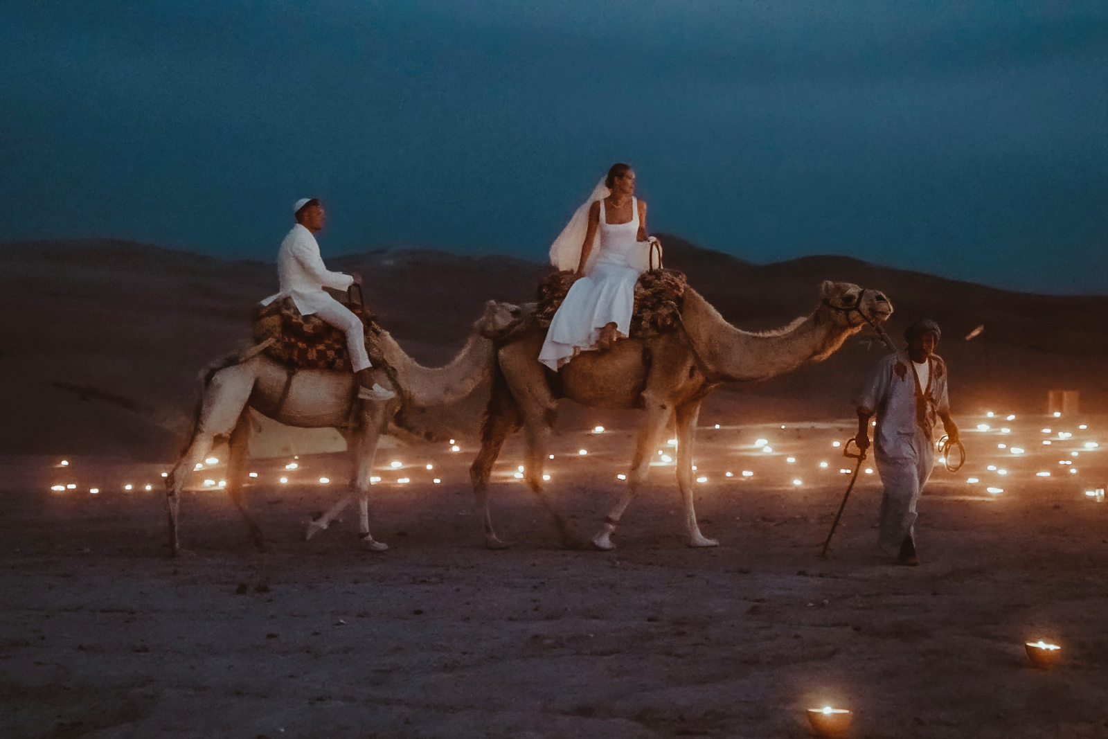 Bridal couple riding on dromedaries in the Agafay desert after their Marrakech Jewish Wedding