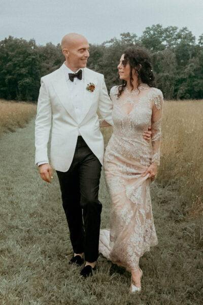 A wedding couple walking in a field Upstate, filmed by their New York Wedding Videographer
