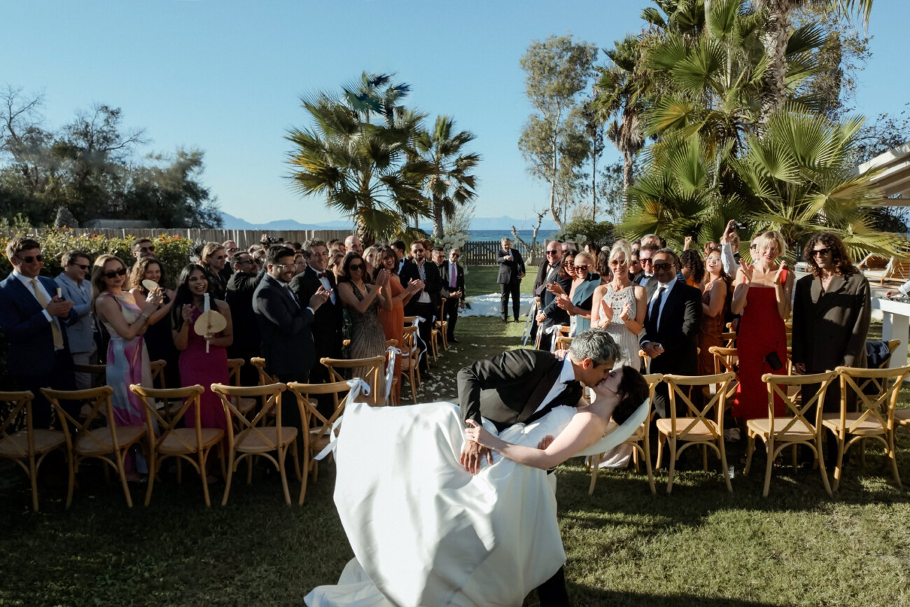 How to Plan a Destination Wedding in Greece, What to Know Before You Begin 6 A kiss after a wedding ceremony with a big applause from the guests in a private Villa in Corfu, ideas on how to plan a destination wedding in Greece