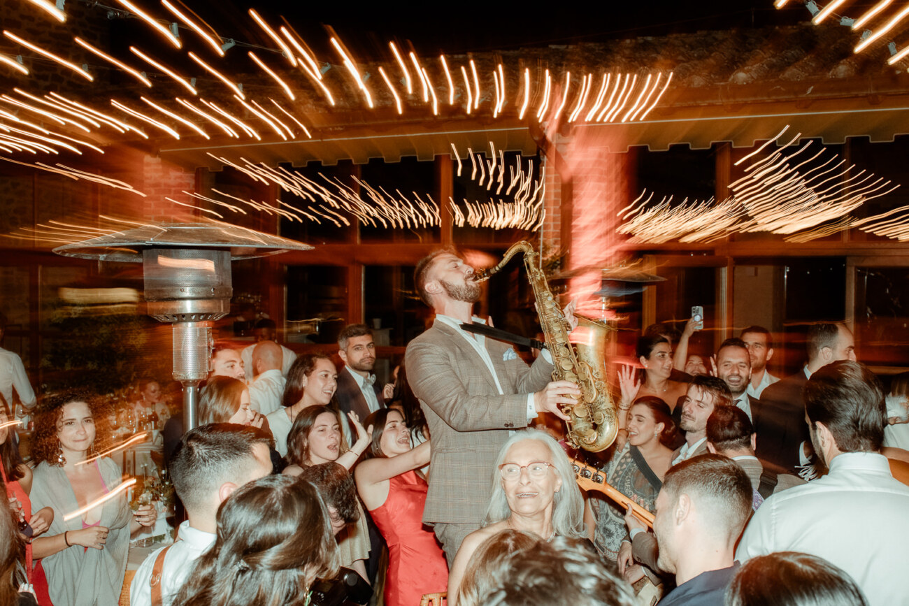 Saxophone player at a destination wedding party in Italy with people dancing around him