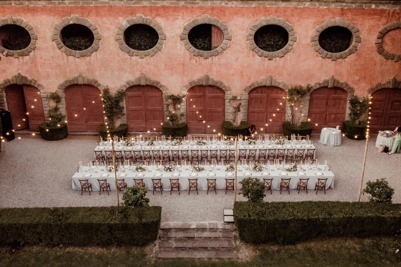 two rows of long tables decorated for a destination wedding reception in Italy