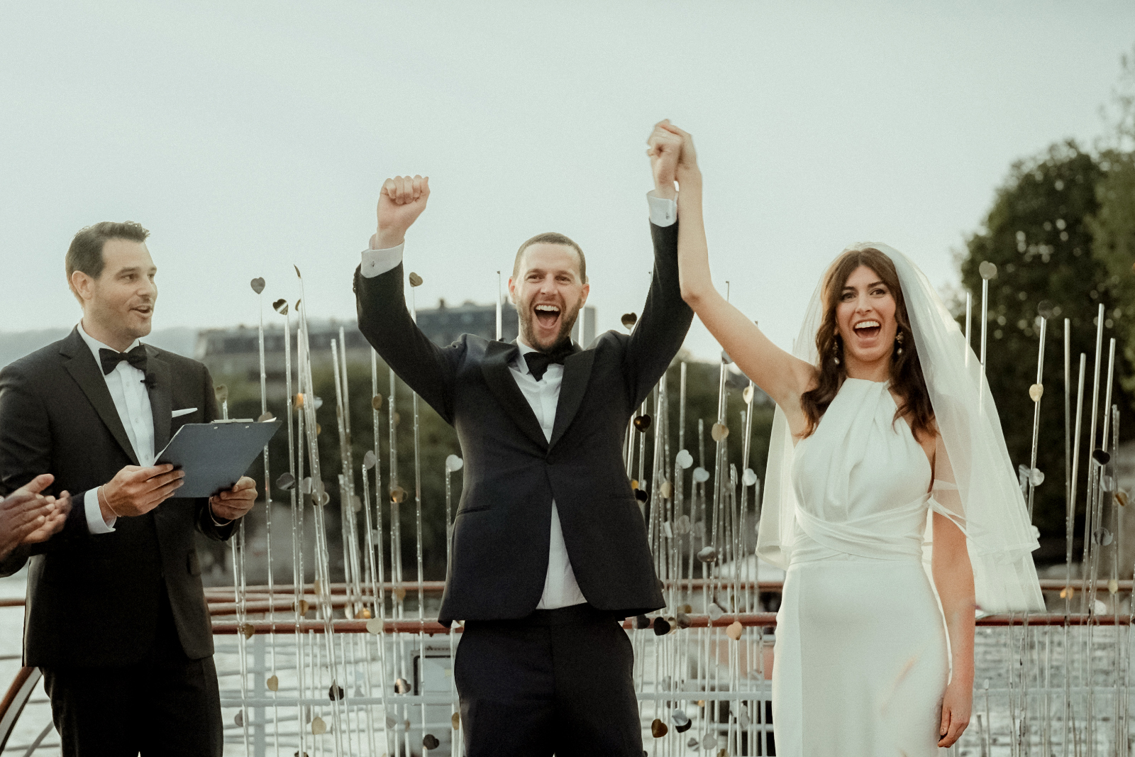 A couple getting married on the Seine and celebrating with hands raised at the end of their ceremony filmed by their Paris Wedding Videographer