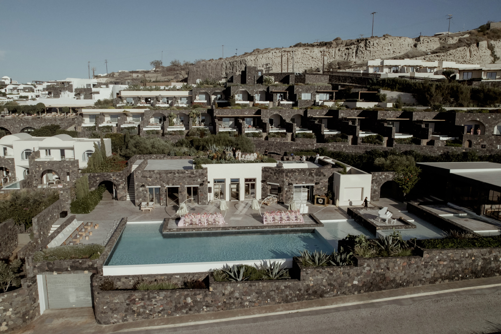 Aerial picture of the Canaves Oia Santorini featuring a wedding reception table setup with pink flowers and crystal chandeliers