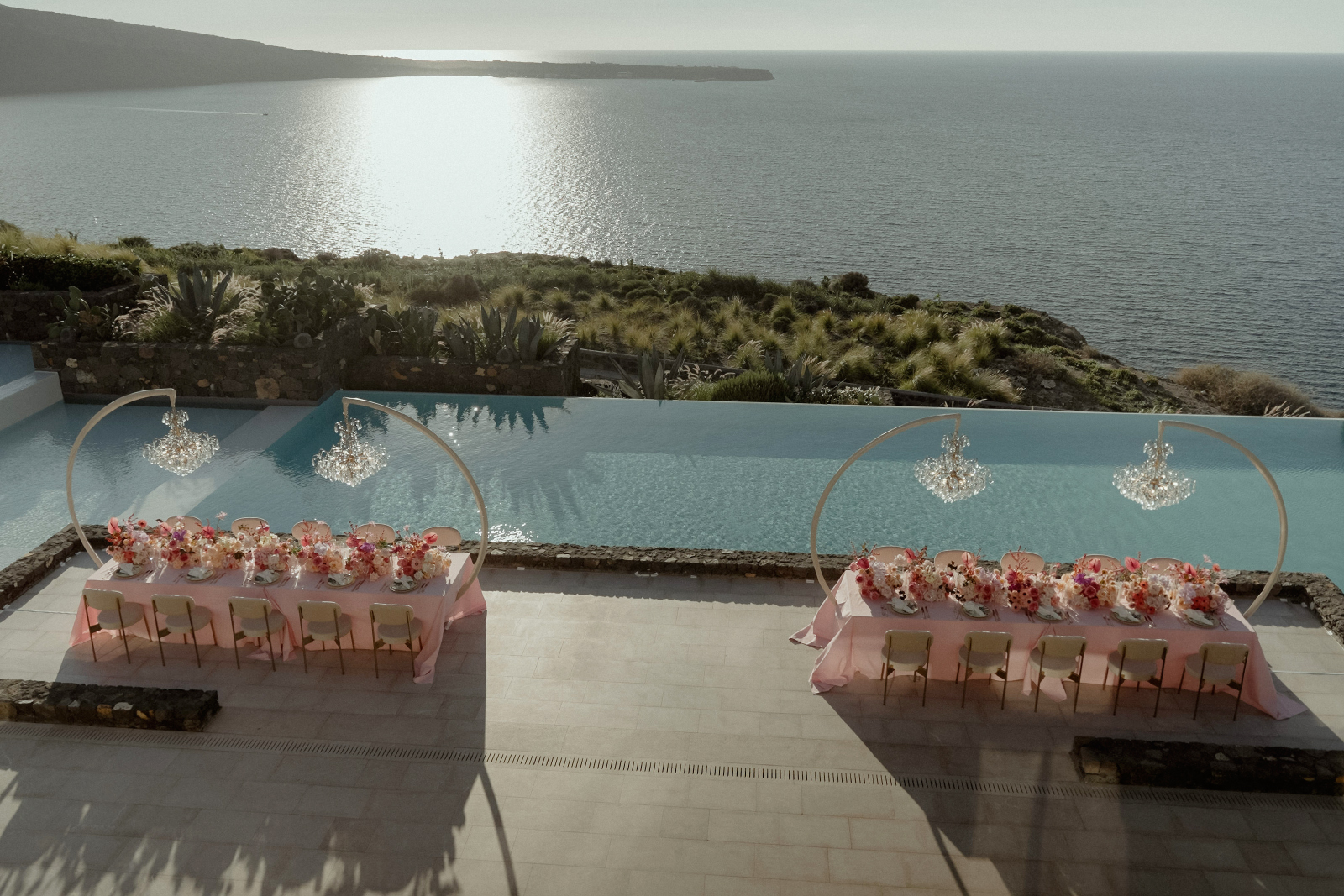 Best wedding venues in Santorini - Ultimate Guide by a local Cinematographer 24 Elegant wedding table decor with pink flowers and crystal chandeliers in Santorini