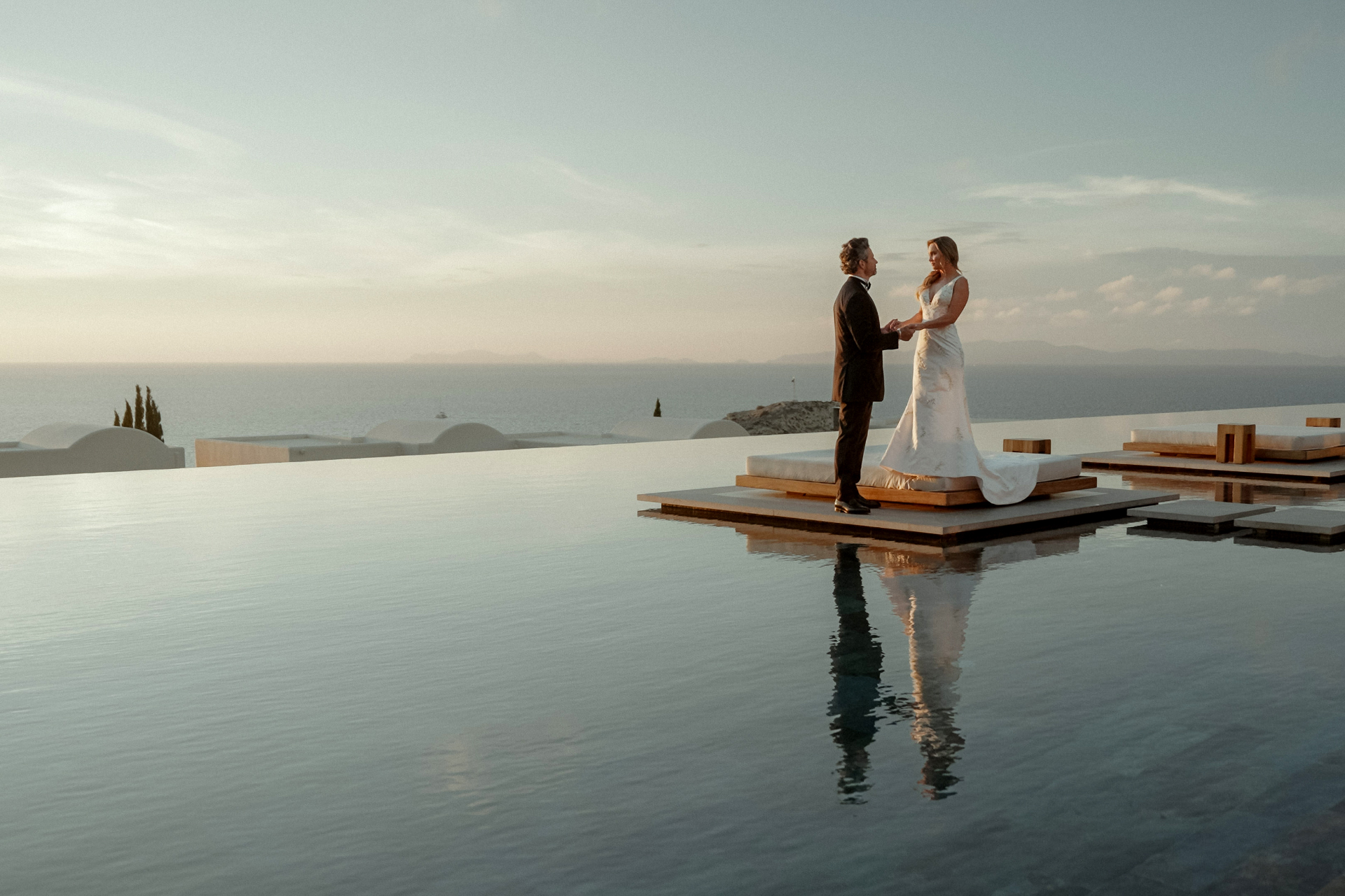Bride and groom holding hands on an infinity pool deck after their Intimate Santorini wedding at Canaves Epitome in Oia