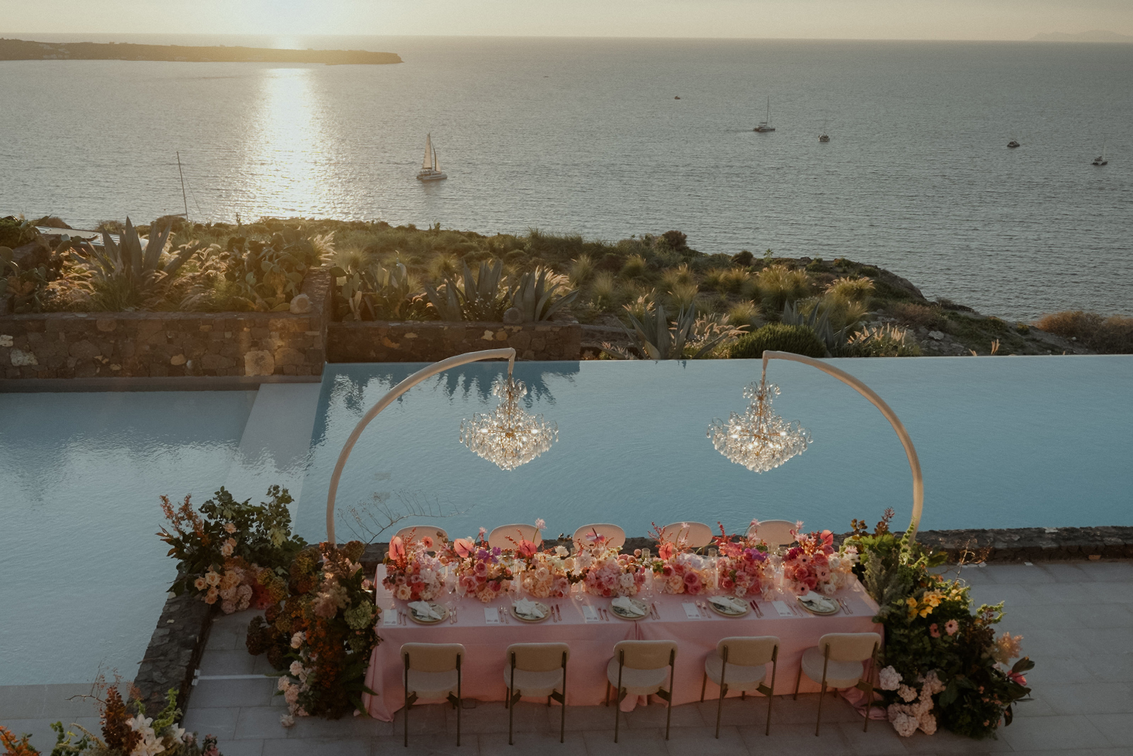 Elegant wedding table decor with pink flowers and crystal chandeliers in Santorini