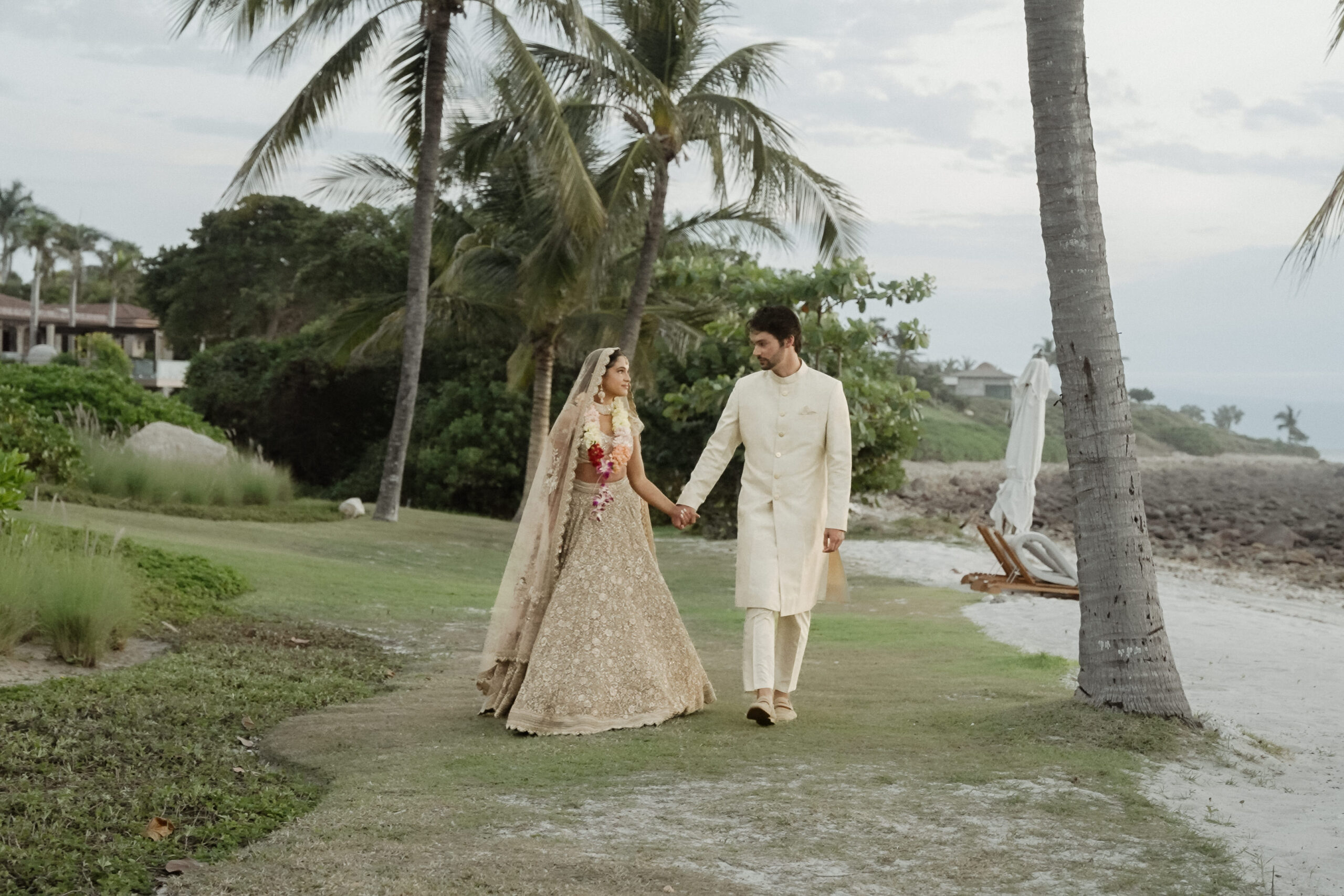 Couple in Indian Wedding attire walking on the beach of St Regis in Punta Mita after their Luxury Indian Wedding in Mexico