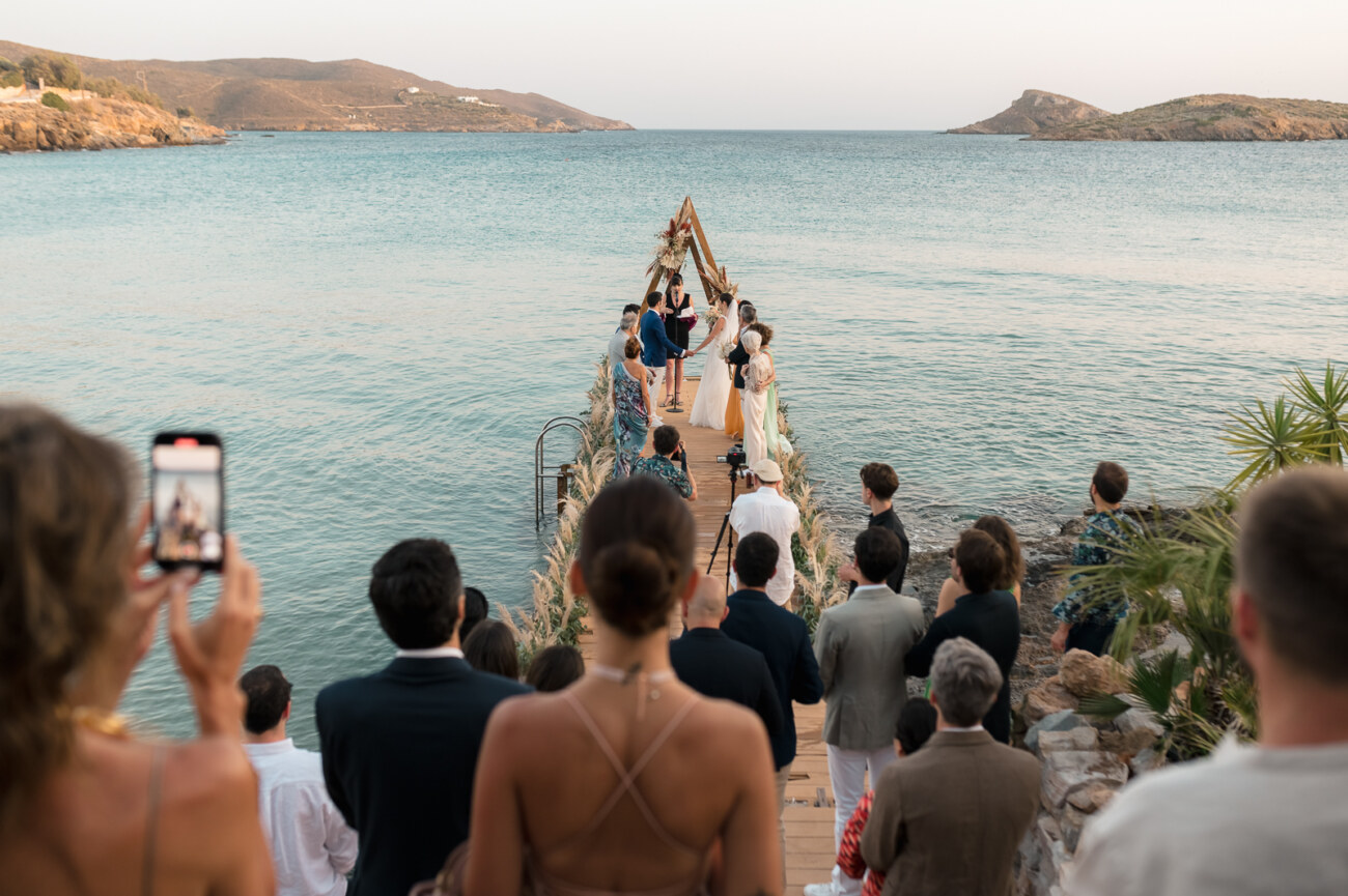 Intimate destination wedding in Greece by the sea with guests and ceremony setup