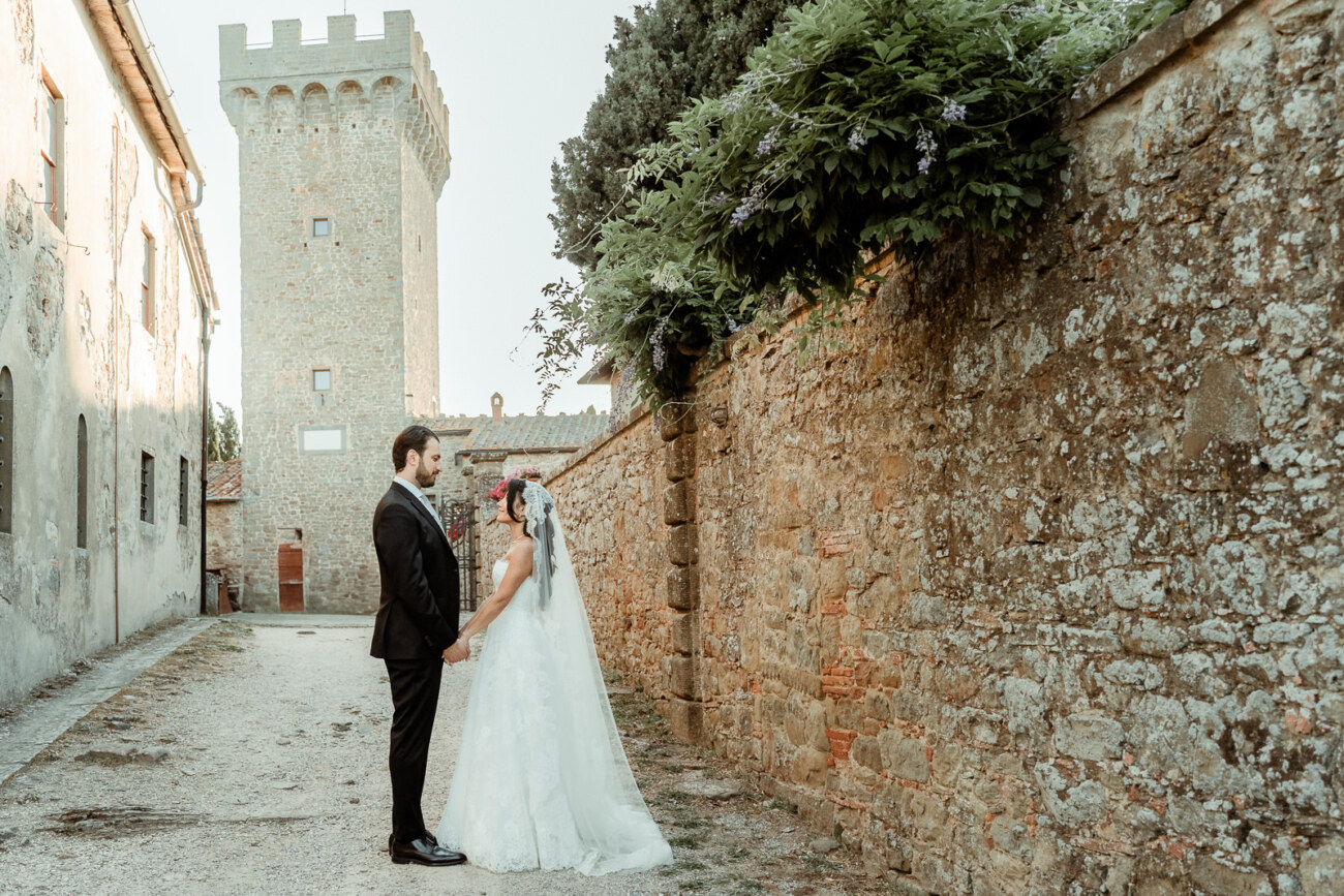 Bridal couple holding hands inside the borgo after their Castello di Gargonza Wedding in Tuscany