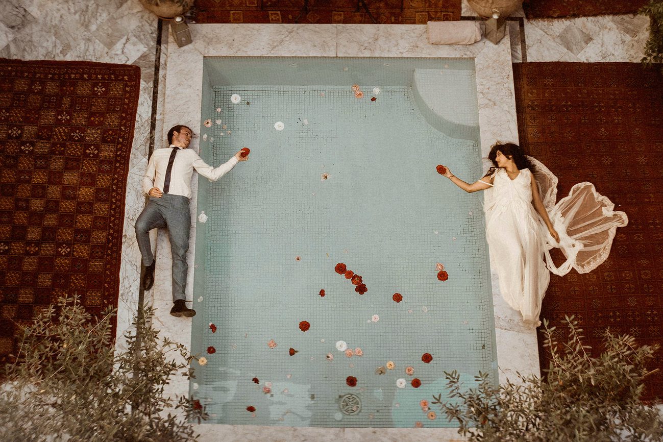 A couple lying on the floor on the two sides of a pool in Morocco filmed by an Elopement Videographer for Intentional and Intimate Celebrations