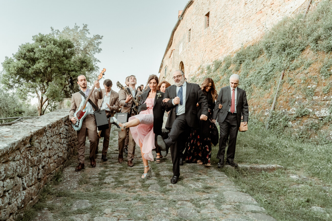 Wedding guests walking to the reception with a live band at Castello di Gargonza in Tuscany