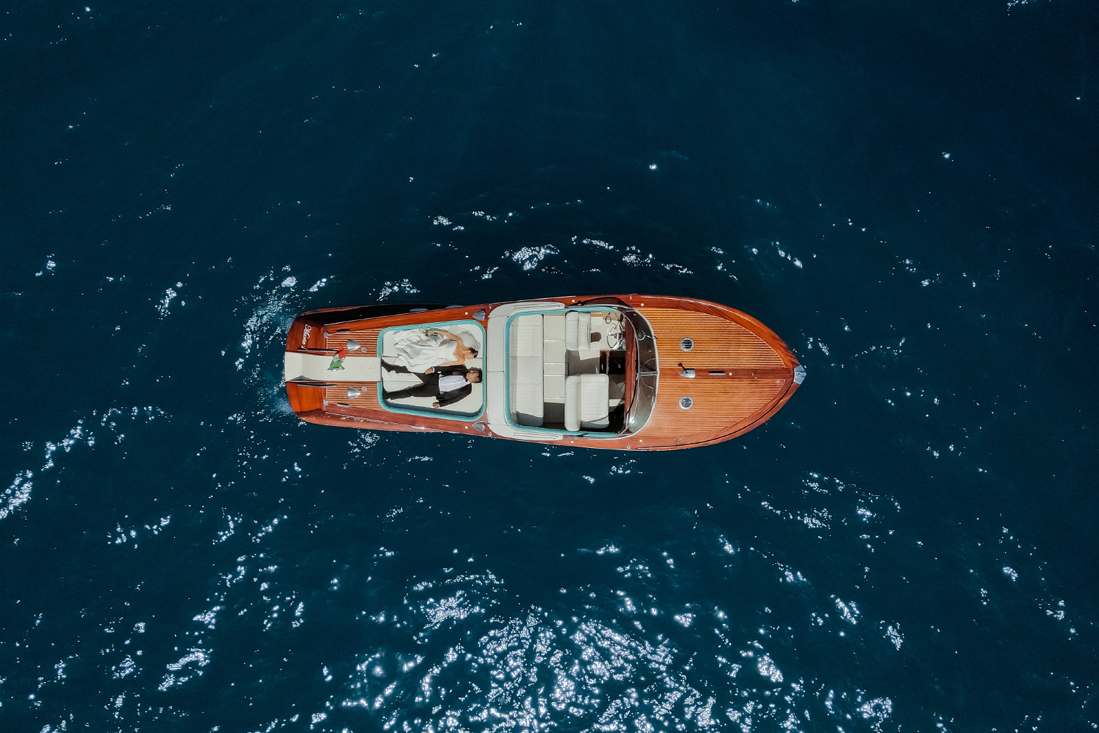 Bride and groom lying on a vintage Riva boat, filmed from above on the Amalfi Coast after their Belmond Caruso Wedding in Ravello