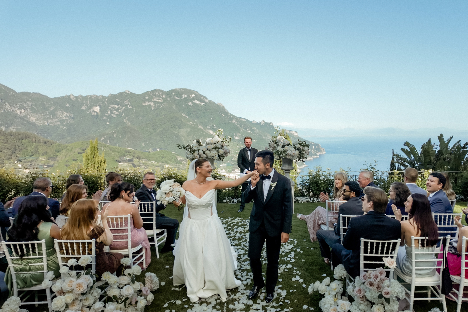 A groom kissing his bride's hand during the ceremony exit of their Belmond Caruso Wedding in Ravello